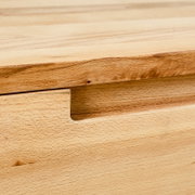 Close-up van een hangende schoenenkast van hout met een natuurlijke nerf en een verzonken handgreep.