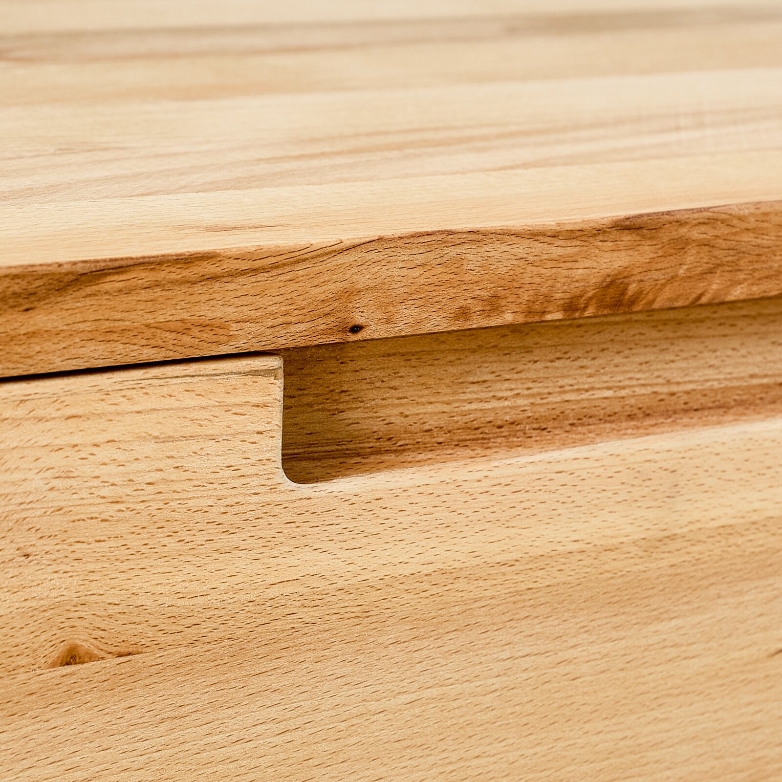 Close-up van een hangende schoenenkast van hout met een natuurlijke nerf en een verzonken handgreep.