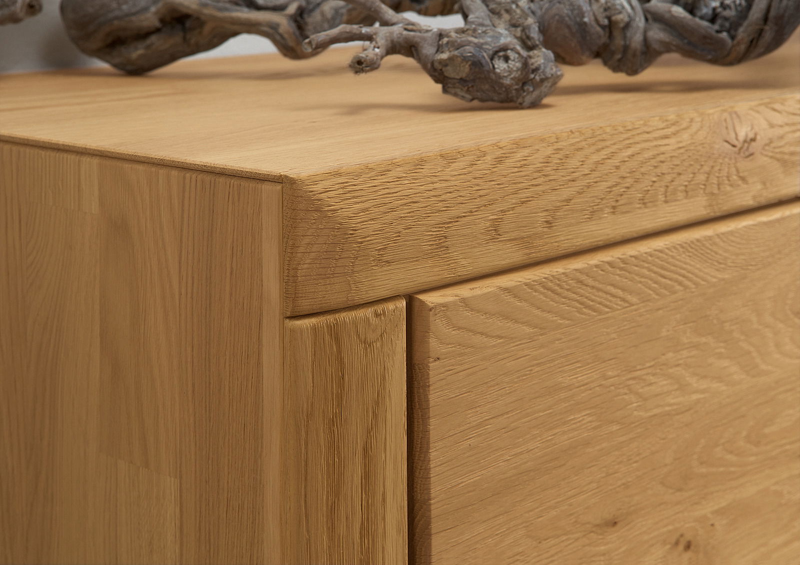 Nahaufnahme einer Holzwandkombination mit natürlicher Maserung und einem dekorativen Ast auf der Oberseite, seitliche Perspektive.