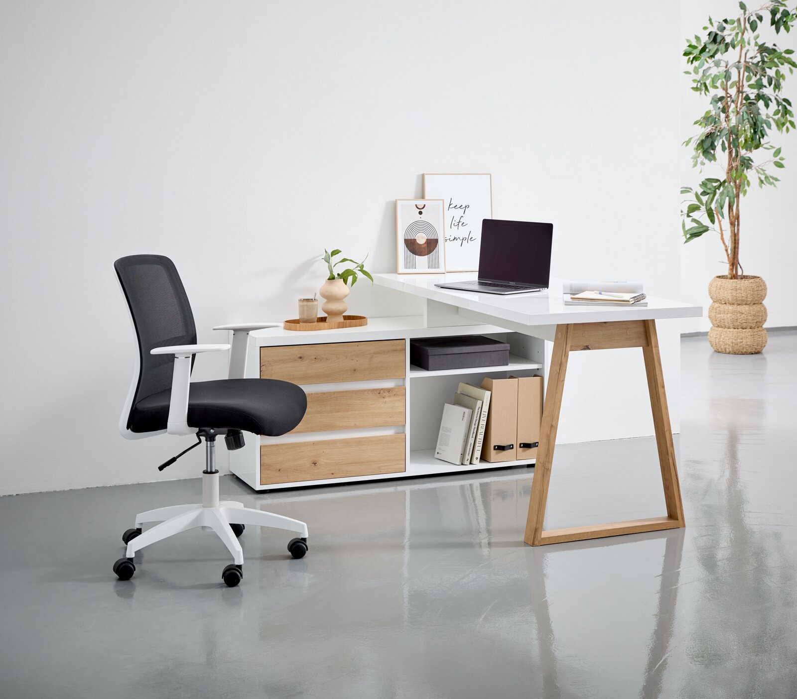 Moderner Drehstuhl in Schwarz und Weiß, seitliche Perspektive, neben einem Schreibtisch mit Holz- und Weißakzenten.
