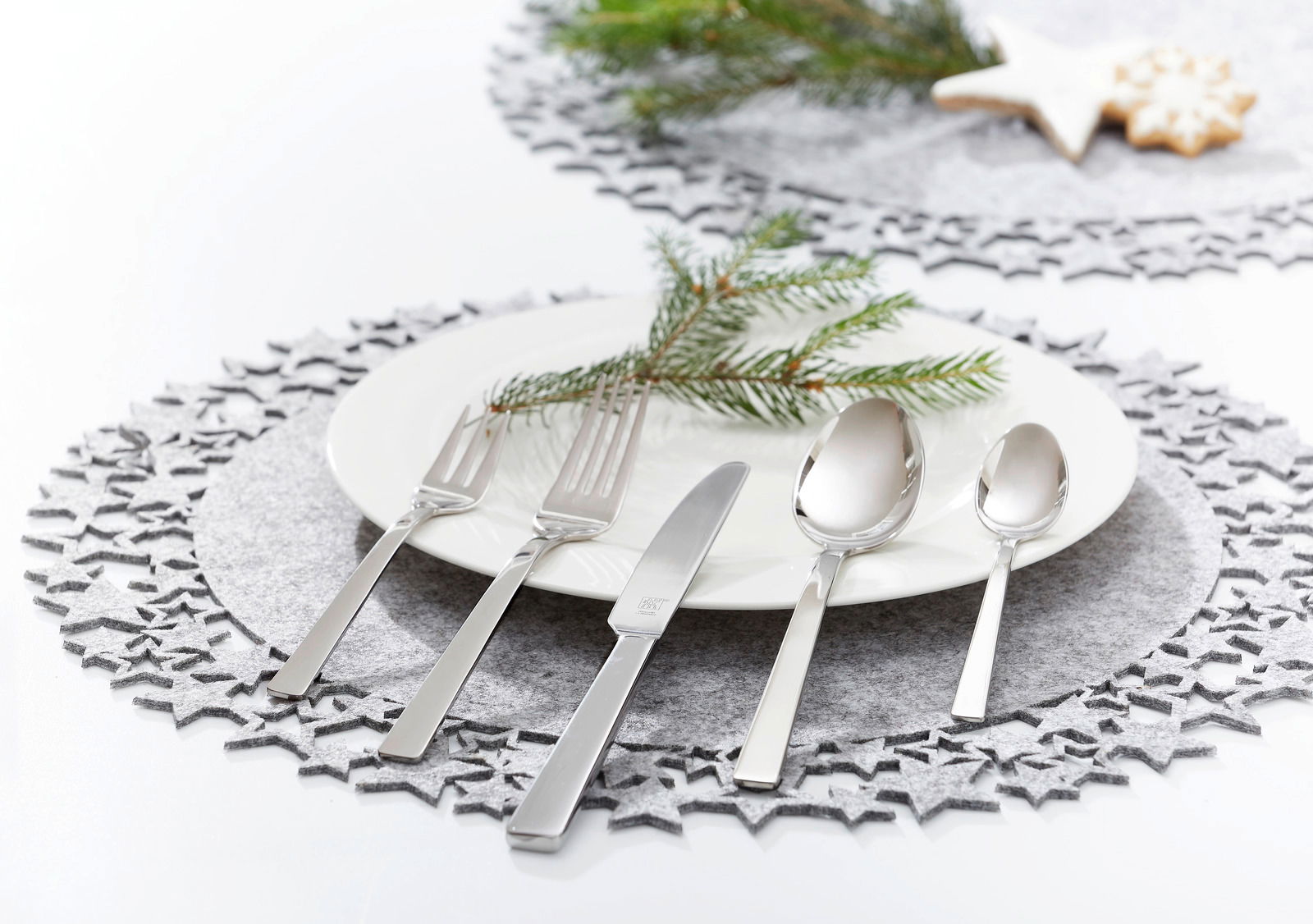 Elegantes, poliertes Besteckset King 60-tlg. auf einem festlich gedeckten Tisch mit Teller, Tannenzweig und weihnachtlicher Dekoration, aus der Vogelperspektive.