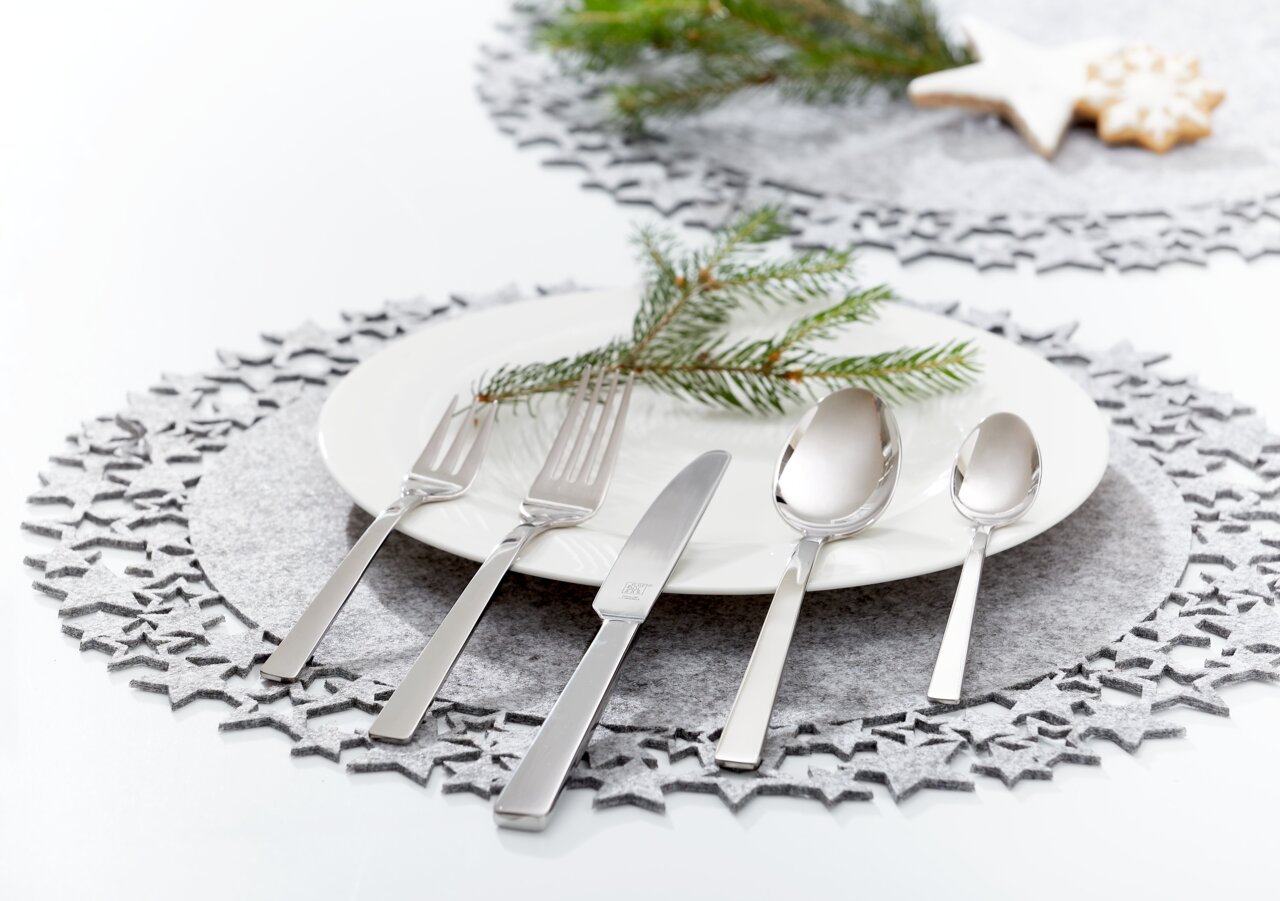 Elegantes, poliertes Besteckset King 60-tlg. auf einem festlich gedeckten Tisch mit Teller, Tannenzweig und weihnachtlicher Dekoration, aus der Vogelperspektive.