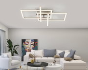 Moderne led-plafondlamp met een geometrisch ontwerp, gezien van onderaf, in een stijlvolle woonkamer met kunstwerken en planten.