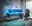 Gaming-Setup mit beleuchtetem Tisch, drei Monitoren, Towerunit und Gaming-Stuhl, seitliche Perspektive