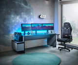 Gaming-Setup mit beleuchtetem Tisch, drei Monitoren, Towerunit und Gaming-Stuhl, seitliche Perspektive