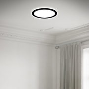 Moderne led-plafondlamp in een elegante ruimte, gezien van onderaf, met een strak, rond ontwerp en een zwarte rand.