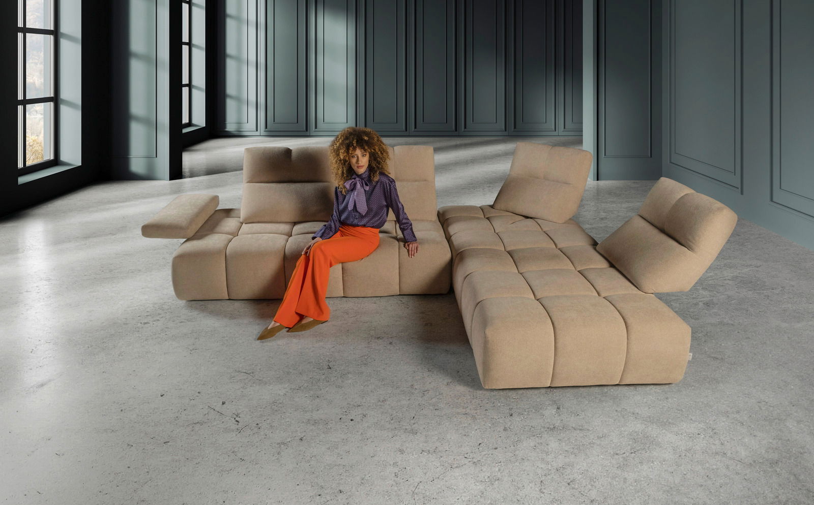 Eckgarnitur in einem modernen Raum, beige Farbe, mit einer Person, die darauf sitzt, Perspektive von vorne.