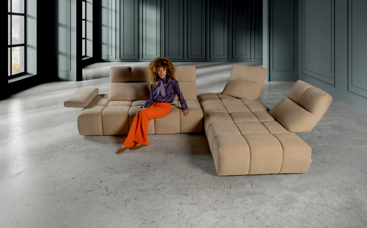 Hoekbank in een moderne ruimte, beige, met iemand die erop zit, gezien van voren.