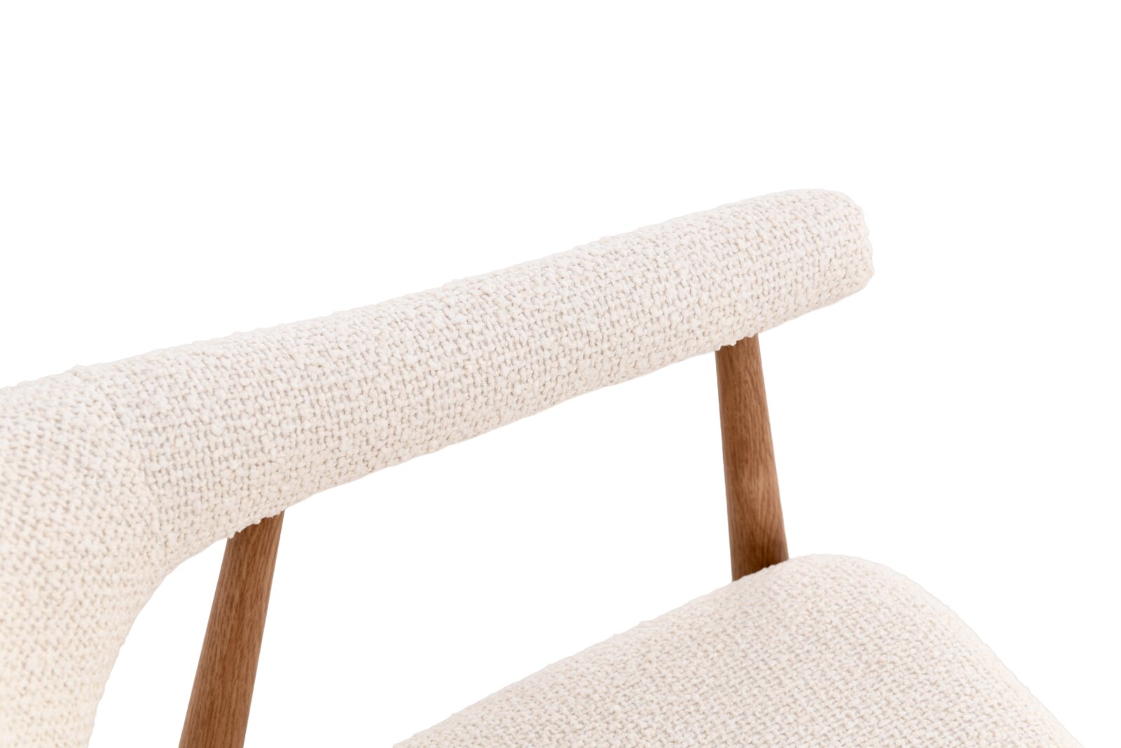 Detailaufnahme eines modernen Stuhls mit cremefarbenem Bouclé-Bezug und Holzgestell, schräg von vorne/oben fotografiert