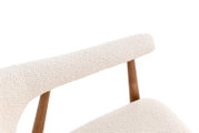 Detailaufnahme eines modernen Stuhls mit cremefarbenem Bouclé-Bezug und Holzgestell, schräg von vorne/oben fotografiert