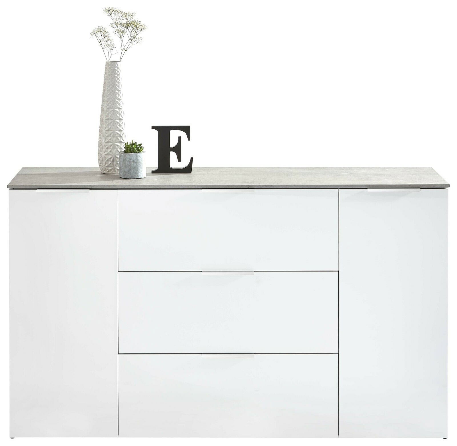 Frontansicht eines weißen XL-Sideboards mit drei Schubladen und zwei Türen, dekoriert mit einer Vase, einer Pflanze und einem Buchstaben E.