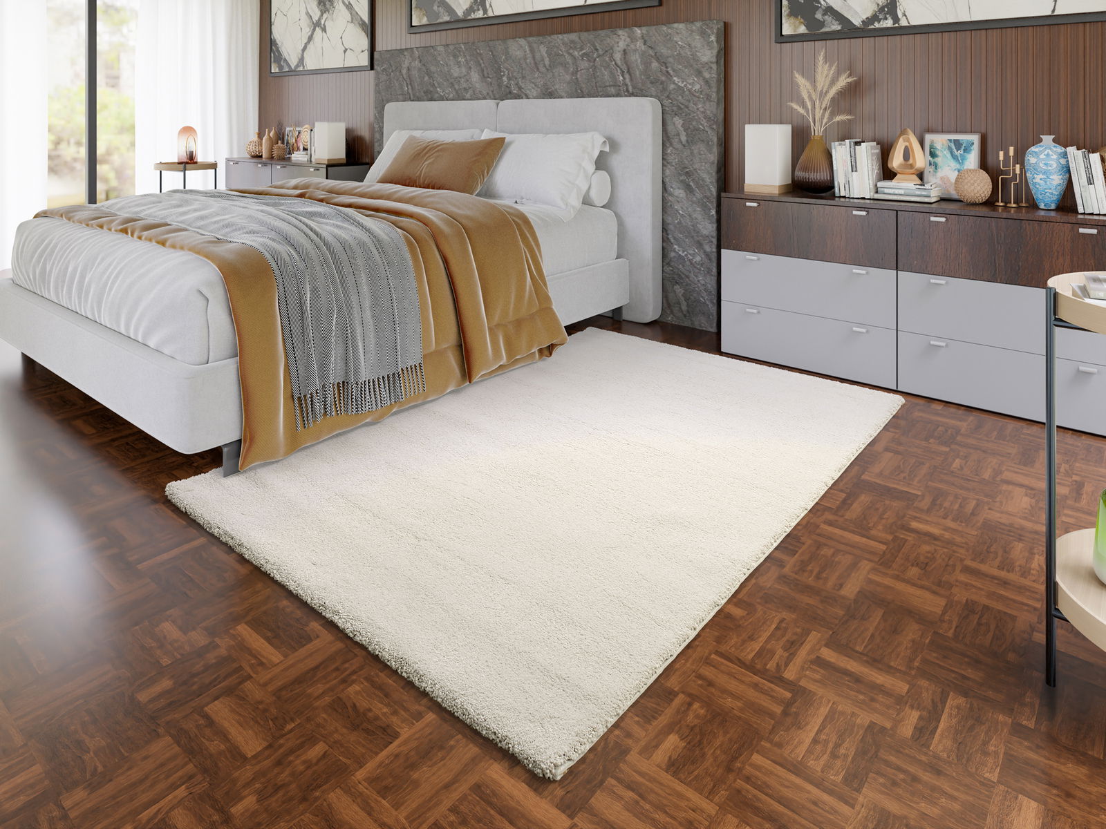 OCI Uni-Teppich NEW VILLA Ein cremefarbener Uni-Teppich liegt in einem modernen Schlafzimmer mit Holzboden, neben einem grauen Bett. Die Perspektive zeigt den Teppich von schräg oben.