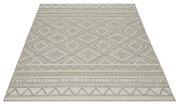 Beige tapijt van platweefsel met een geometrisch ruit- en randpatroon in natuurlijke tinten, van voren en van bovenaf gefotografeerd vanuit een licht perspectief.