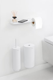 Moderner Toilettenpapierhalter mit Ablage, seitliche Perspektive, mit Duftstäbchen und Smartphone auf der Ablage.