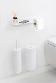 Moderner Toilettenpapierhalter mit Ablage, seitliche Perspektive, mit Duftstäbchen und Smartphone auf der Ablage.