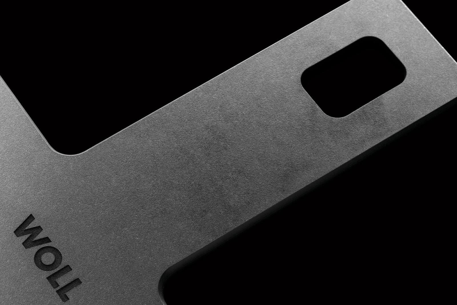 Nahaufnahme eines grauen Schneidebretts mit rechteckigem Griffloch, diagonale Perspektive