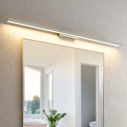 Moderne LED-Wandleuchte über einem Spiegel, seitliche Perspektive