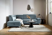 Moderne L-vormige hoekbank in een stijlvolle woonkamer, met blauwe bekleding, versierd met kussens en een deken, gezien vanuit het perspectief linksvoor.