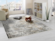 Designer Teppich in einem modernen Wohnzimmer mit hellem Boden, einem weißen Regal und einem Sessel. Perspektive von schräg oben.