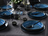 Elegantes 18-teiliges Tellerset in Blau, auf einem gedeckten Tisch mit Gläsern und Besteck, aus der Vogelperspektive fotografiert.