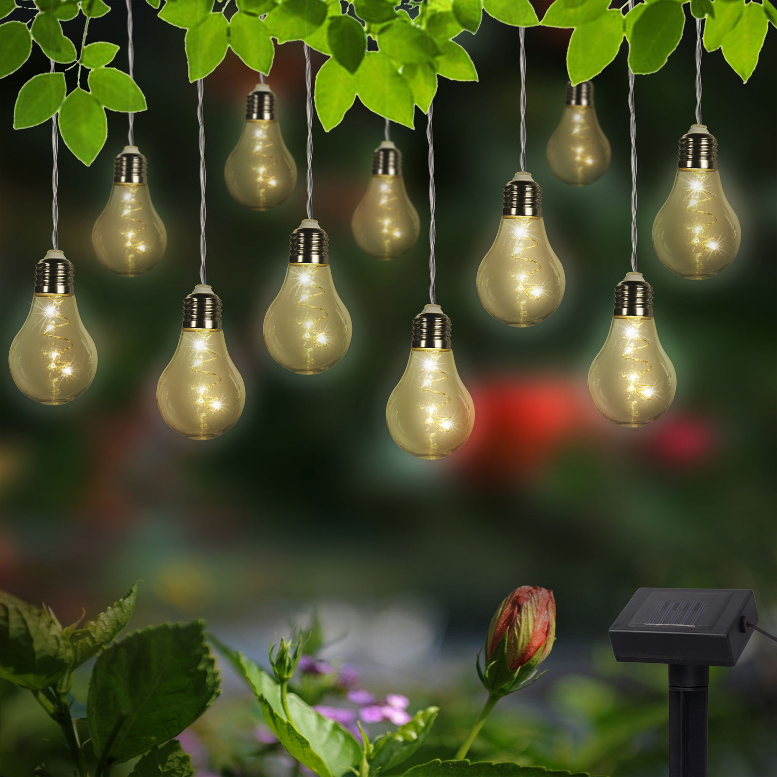 Solarbetriebene Lichterkette mit Glühbirnen-Design, aufgehängt in einem Garten mit grünen Blättern und Blumen im Hintergrund, seitliche Perspektive.