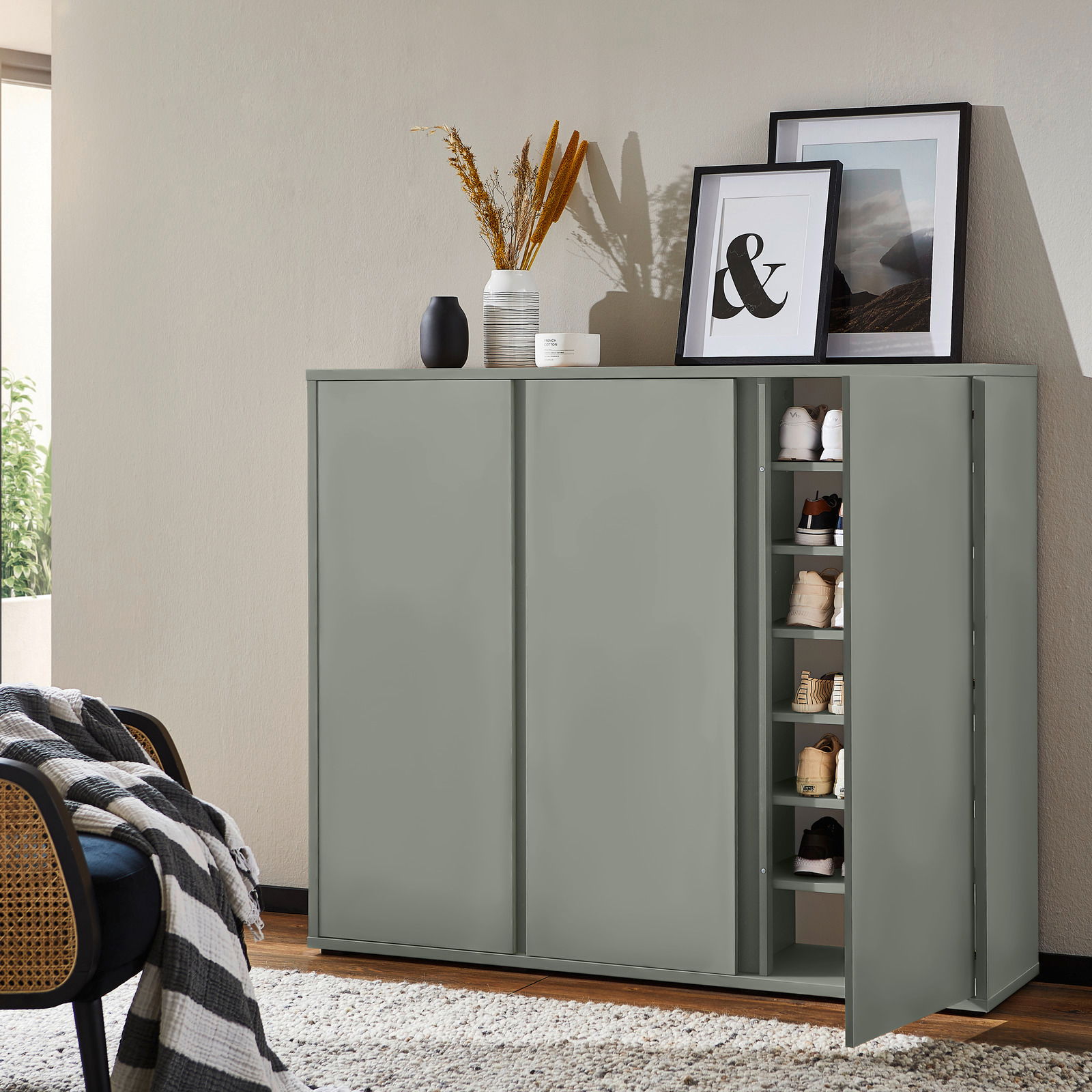 Moderner Schuhschrank in einem Wohnzimmer, teilweise geöffnet, mit mehreren Paar Schuhen sichtbar. Perspektive von vorne.