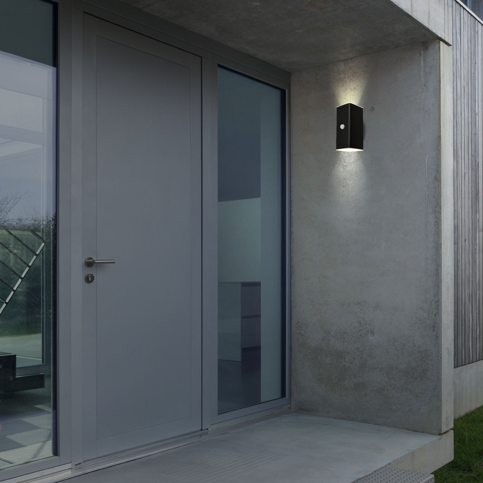 Briloner Akku-Außenwandleuchte Moderne Akku-Außenwandleuchte an einer Betonwand neben einer Haustür, seitliche Perspektive
