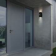 Moderne Akku-Außenwandleuchte an einer Betonwand neben einer Haustür, seitliche Perspektive