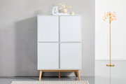 Frontale Ansicht eines modernen weißen Highboards mit vier Türen und Holzbeinen, dekoriert mit Vasen und Büchern auf der Oberseite, neben einer goldenen Stehlampe.