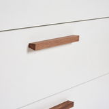 Nahaufnahme einer weißen Wickelkommode mit hölzernen Griffen, seitliche Perspektive