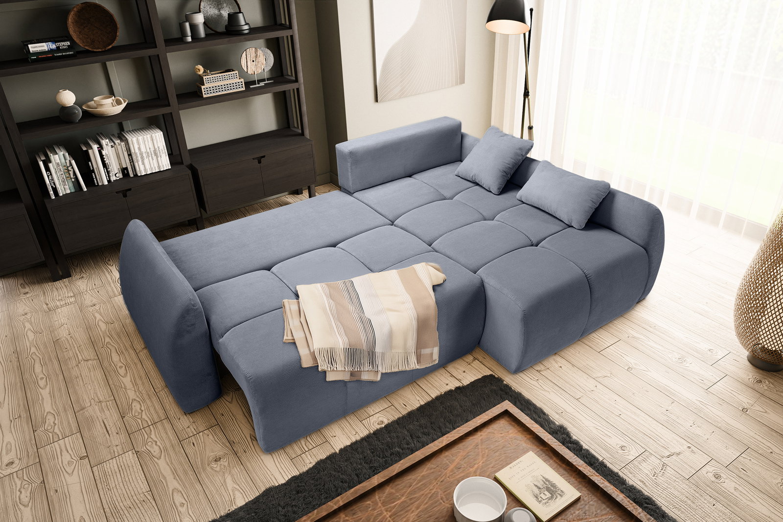 Eckschlafsofa in blauer Farbe, ausgeklappt als Bett, mit zwei Kissen und einer Decke, in einem modernen Wohnzimmer mit Holzfußboden und Bücherregal, Perspektive von oben.