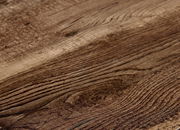 Nahaufnahme einer Holzoberfläche mit natürlicher Maserung, perspektivisch von der Seite betrachtet.