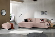 Modernes Wohnzimmer mit roséfarbenem Cord-Ecksofa mit Chaiselongue und passendem Hocker, dekoriert mit Kissen, aufgenommen in frontaler Perspektive leicht von links.