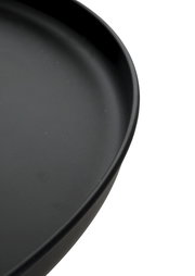 Schwarzer, runder Teller mit leicht erhöhtem Rand in Nahaufnahme, schräg von oben fotografiert.