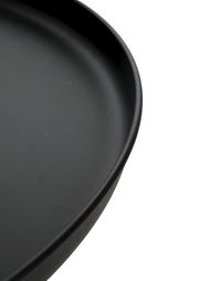 Schwarzer, runder Teller mit leicht erhöhtem Rand in Nahaufnahme, schräg von oben fotografiert.