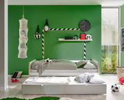 Jugendbett in einem sportlich dekorierten Zimmer mit grünem Hintergrund, Fußballthema und zusätzlichem Ausziehbett, seitliche Perspektive