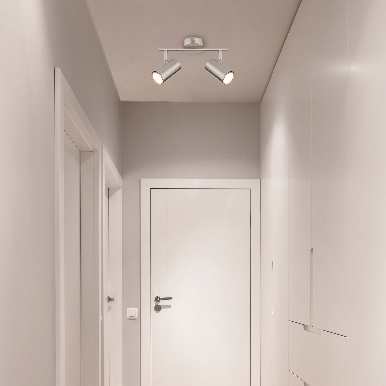 Zweiflammiger Deckenstrahler in modernem Design, montiert an der Decke eines Flurs, aus der Perspektive von unten betrachtet.