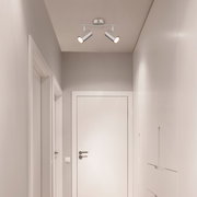 Zweiflammiger Deckenstrahler in modernem Design, montiert an der Decke eines Flurs, aus der Perspektive von unten betrachtet.