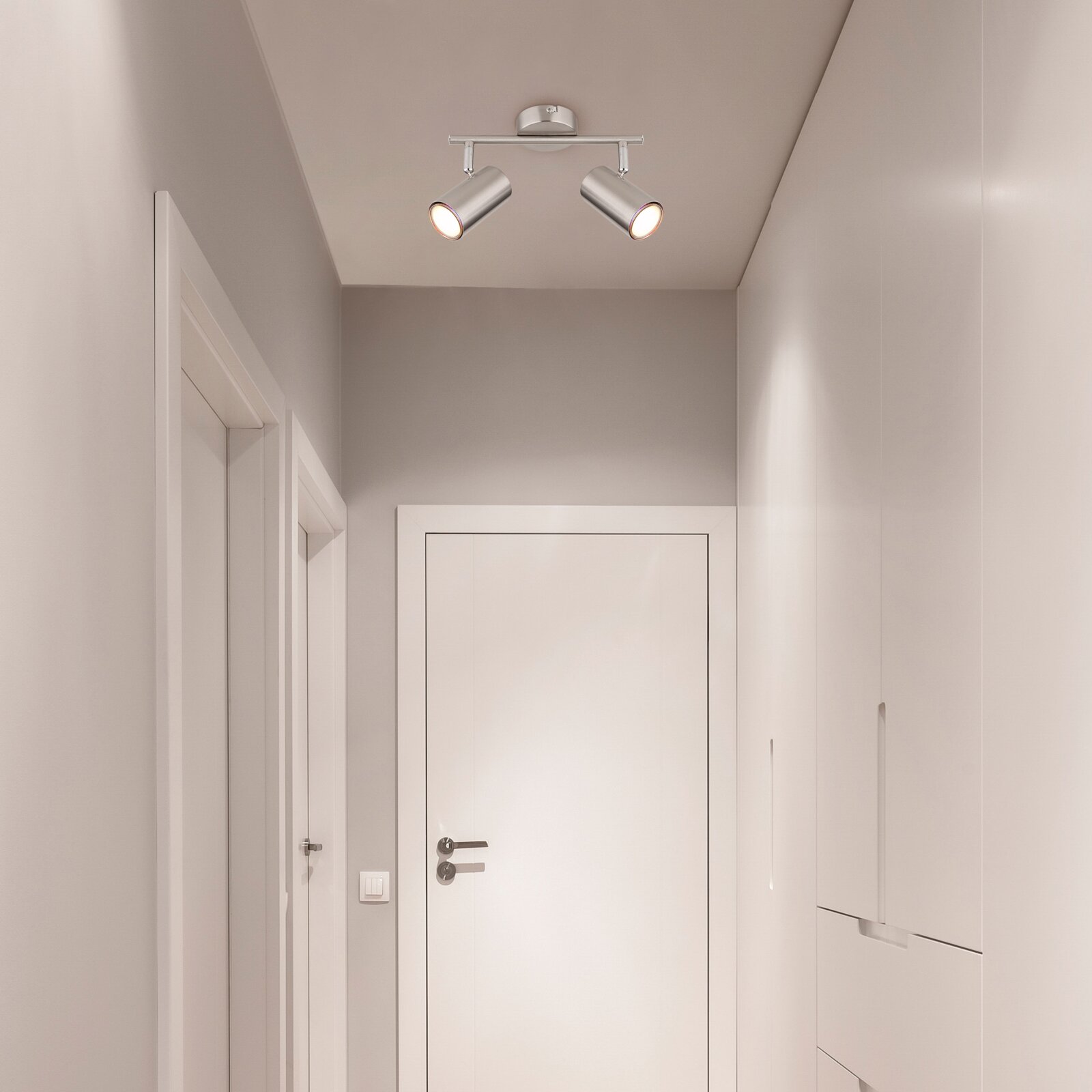 Tweelampige plafondspot in modern design, gemonteerd aan het plafond van een gang, gezien vanuit het perspectief van beneden.