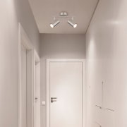 Tweelampige plafondspot in modern design, gemonteerd aan het plafond van een gang, gezien vanuit het perspectief van beneden.