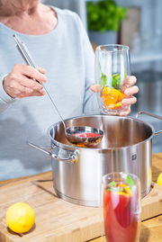 Person schöpft mit einem Schöpflöffel Pro aus einem Topf, seitliche Perspektive.