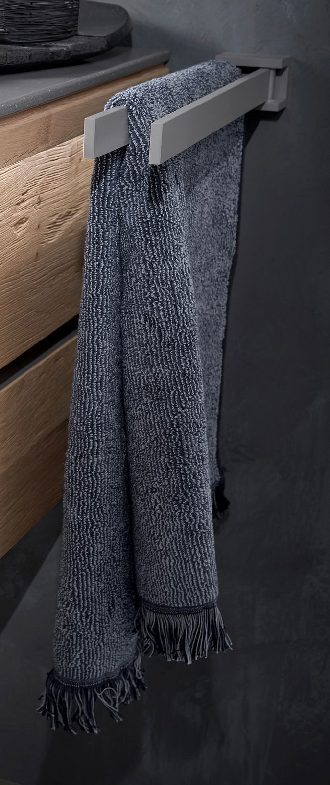 Moderner Handtuchhalter aus Metall mit einem dunkelblauen Handtuch, seitliche Perspektive.