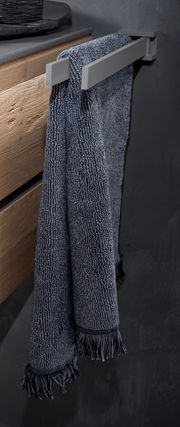 Moderner Handtuchhalter aus Metall mit einem dunkelblauen Handtuch, seitliche Perspektive.
