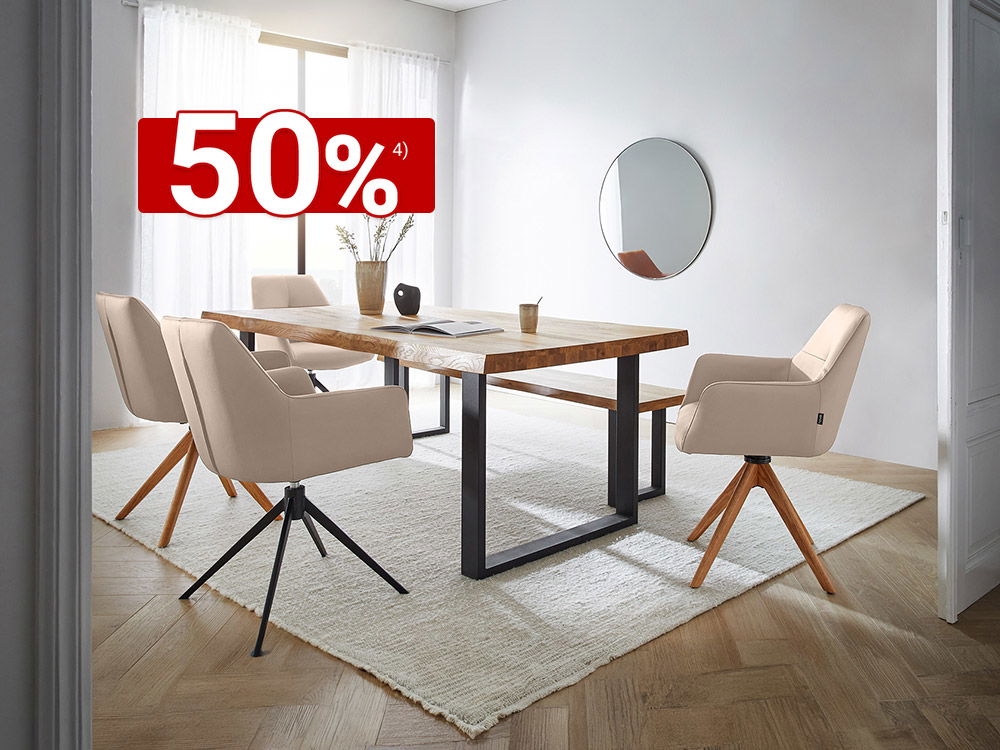 Helles Esszimmer mit Holztisch, vier beigen Drehstühlen, Teppich und rundem Wandspiegel