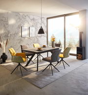 Moderner Esstisch mit stilvollen Stühlen in einem hellen Raum mit Blick auf die Berge, seitliche Perspektive.