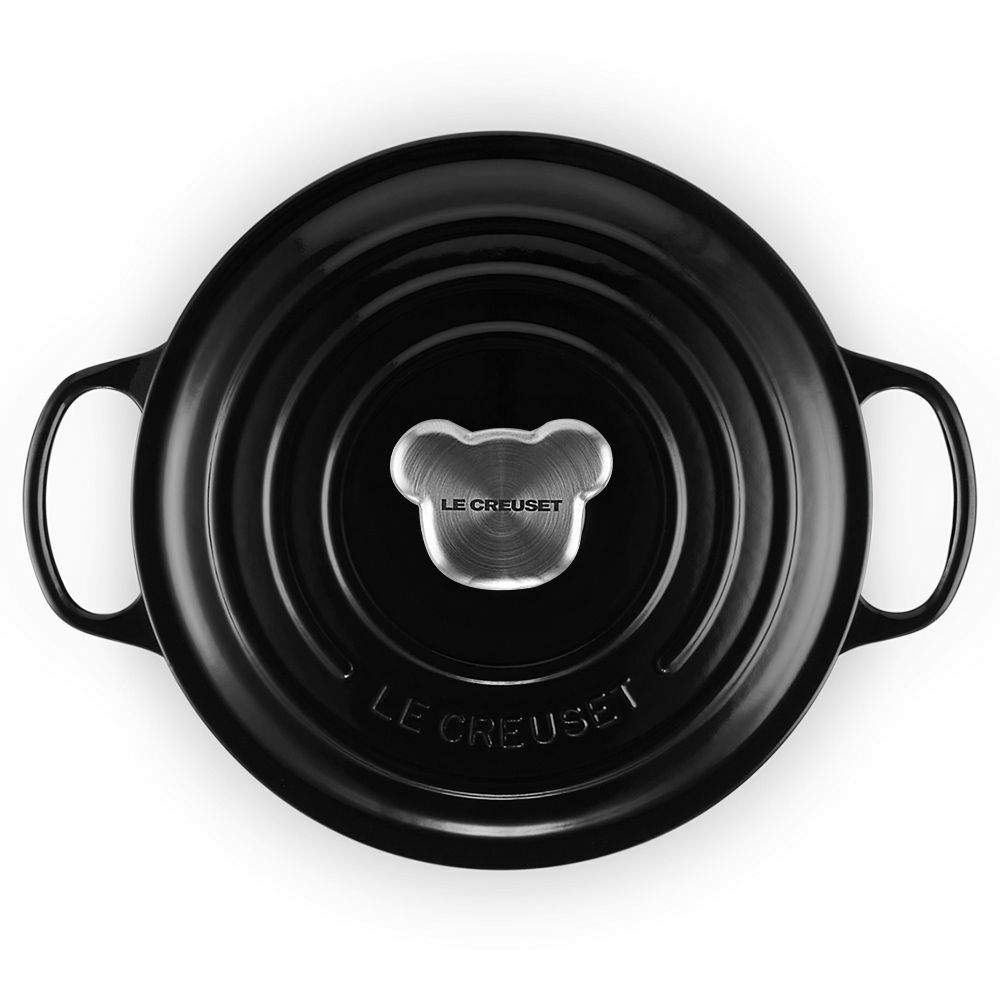 Vogelperspektive auf einen schwarzen Le Creuset Topf mit einem bärenförmigen Edelstahlknauf auf dem Deckel.