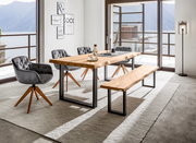 Moderner Esstisch aus Holz mit Metallbeinen, umgeben von grauen Stühlen und einer Bank, in einem hellen Raum mit Blick auf einen See. Perspektive: seitlich.