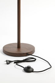 Nahaufnahme der Basis einer Stehleuchte mit Holzoptik, Kabel und Fußschalter sichtbar.