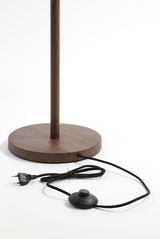 Nahaufnahme der Basis einer Stehleuchte mit Holzoptik, Kabel und Fußschalter sichtbar.