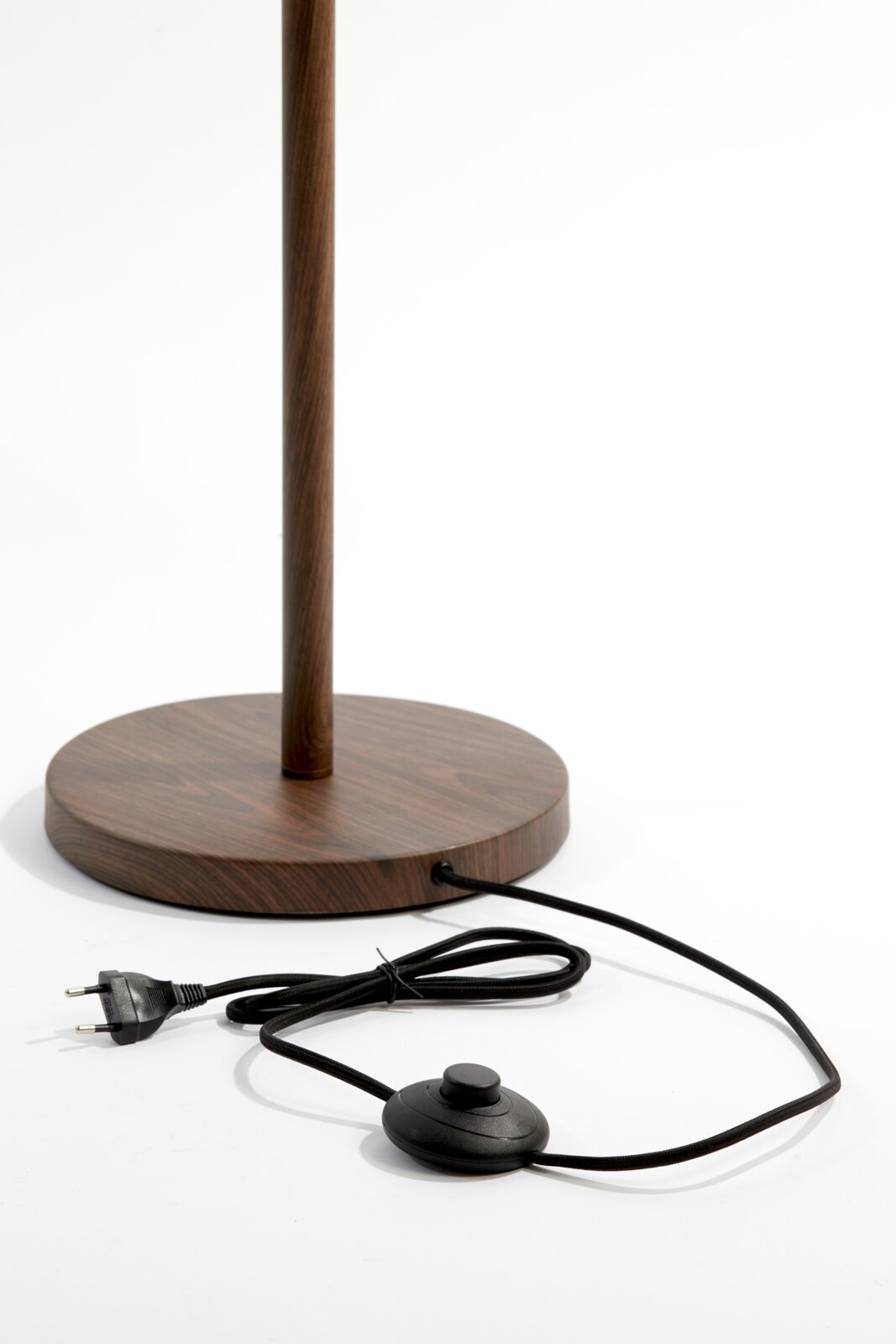 Nahaufnahme der Basis einer Stehleuchte mit Holzoptik, Kabel und Fußschalter sichtbar.